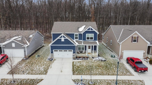 traditional home featuring roof with shingles, a porch, concrete driveway, stone siding, and board and batten siding