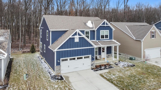 craftsman house with stone siding, board and batten siding, driveway, and roof with shingles