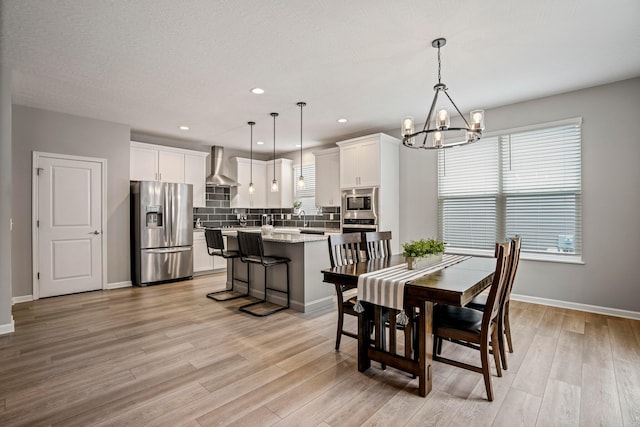 dining room featuring an inviting chandelier, light wood-style floors, and baseboards