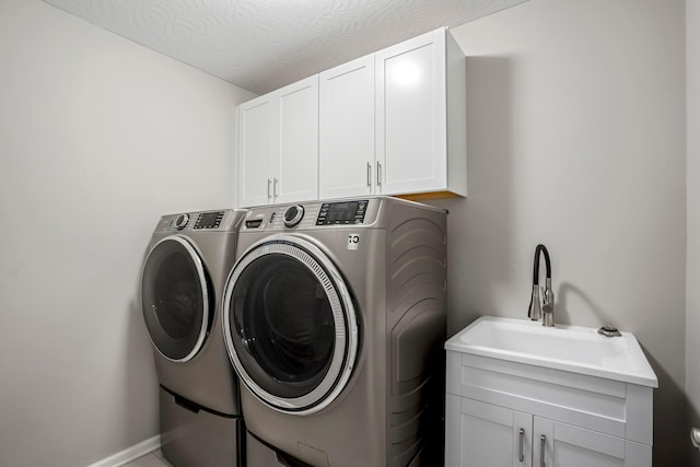 clothes washing area featuring a sink, cabinet space, and washer and clothes dryer