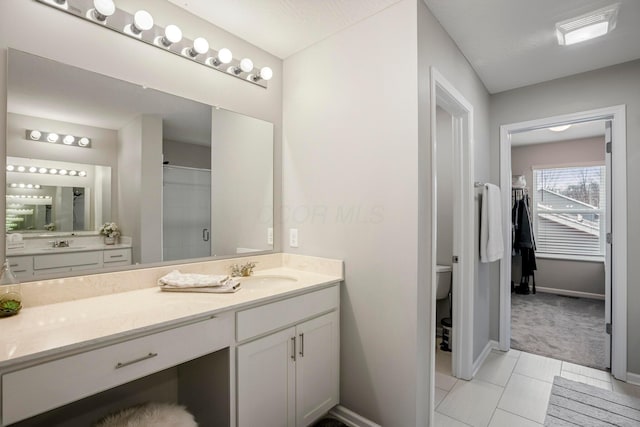 full bath featuring baseboards, vanity, toilet, and a shower stall