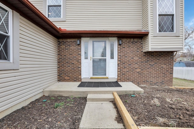 property entrance with brick siding and fence