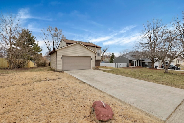 view of front facade featuring a front yard, concrete driveway, fence, and an attached garage