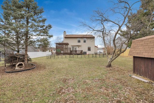 rear view of house featuring fence, a chimney, and a lawn