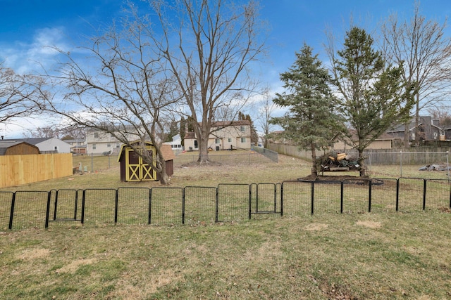 view of yard featuring a residential view, a gate, fence, an outdoor structure, and a shed