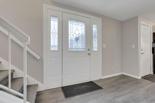 foyer entrance featuring stairway, wood finished floors, and baseboards