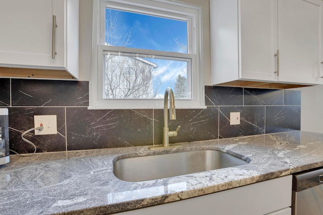 kitchen with a sink, white cabinetry, backsplash, light stone countertops, and dishwasher