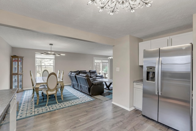 dining room featuring plenty of natural light, light wood-style flooring, baseboards, and a textured ceiling