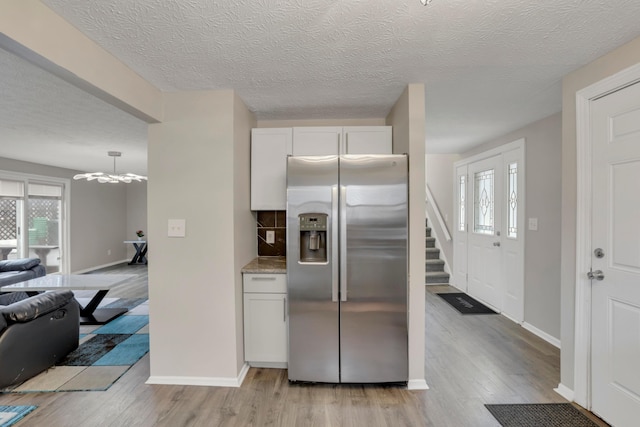 kitchen featuring light wood-type flooring, an inviting chandelier, baseboards, and stainless steel refrigerator with ice dispenser