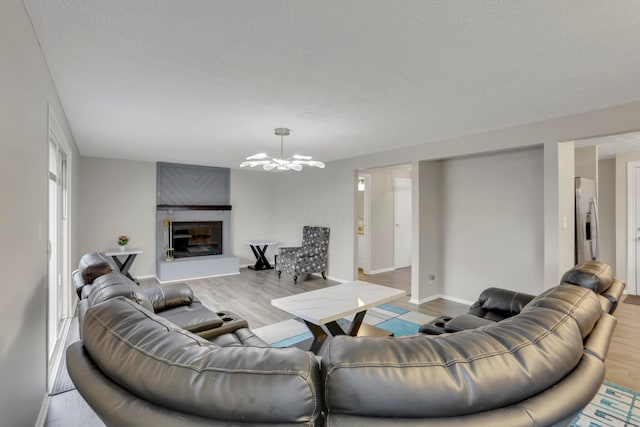 living room with light wood-style floors, baseboards, a fireplace, and a chandelier