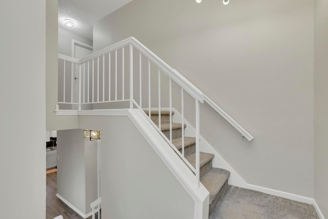 stairway with baseboards and carpet flooring