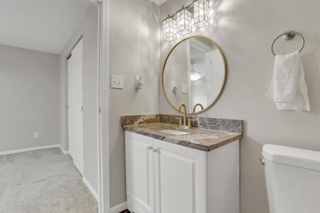 half bathroom featuring toilet, baseboards, and vanity