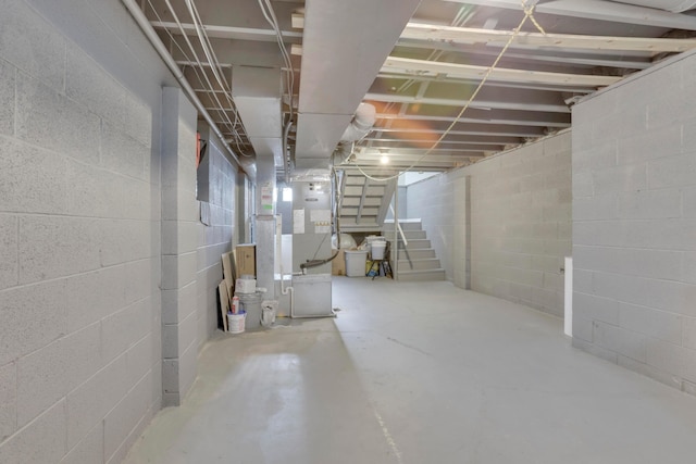 unfinished basement featuring concrete block wall and stairs