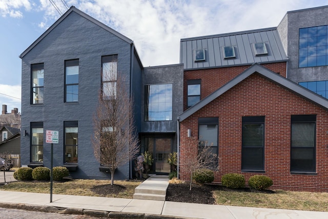 view of front facade with a standing seam roof, metal roof, and brick siding