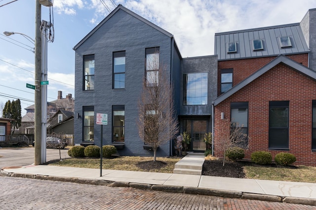 view of front of house featuring a standing seam roof, brick siding, and metal roof