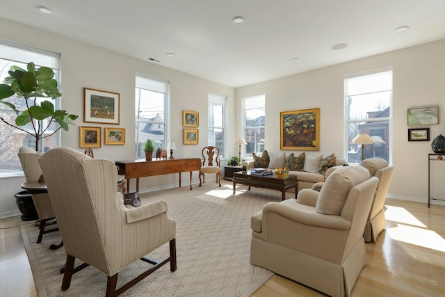 living area with light wood-style floors, visible vents, and baseboards