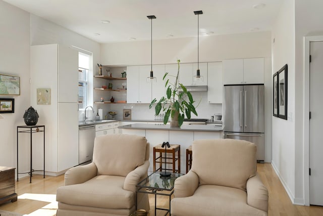 kitchen featuring open floor plan, stainless steel appliances, under cabinet range hood, and white cabinets