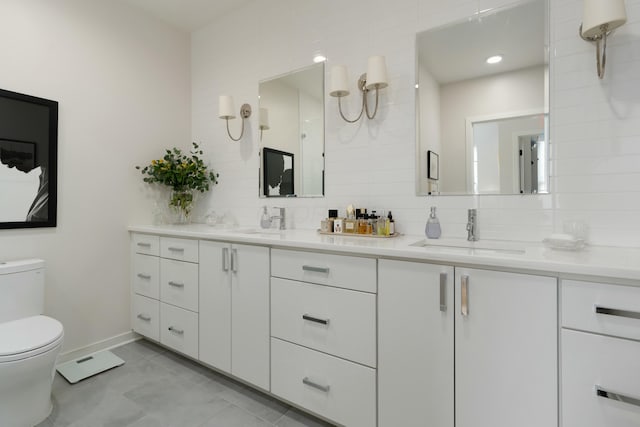 bathroom featuring toilet, tasteful backsplash, double vanity, and a sink