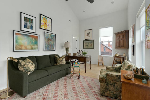 living room with ceiling fan, high vaulted ceiling, light wood finished floors, and visible vents