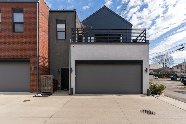 view of front of property with concrete driveway, a balcony, and stucco siding