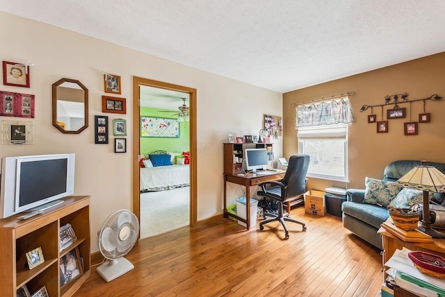 office area featuring wood-type flooring, a textured ceiling, and baseboards