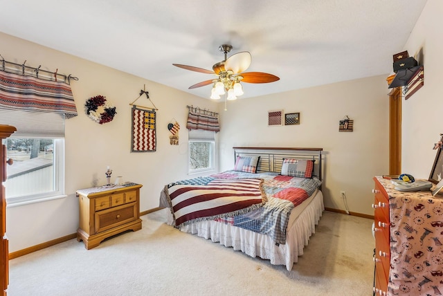 bedroom with multiple windows, light colored carpet, and baseboards