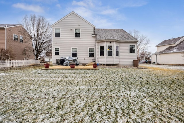 rear view of property featuring a shingled roof and fence