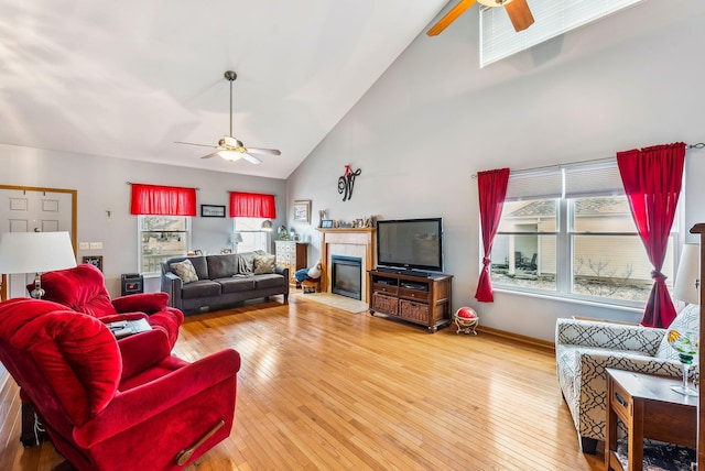 living room with a ceiling fan, wood-type flooring, a fireplace, and high vaulted ceiling