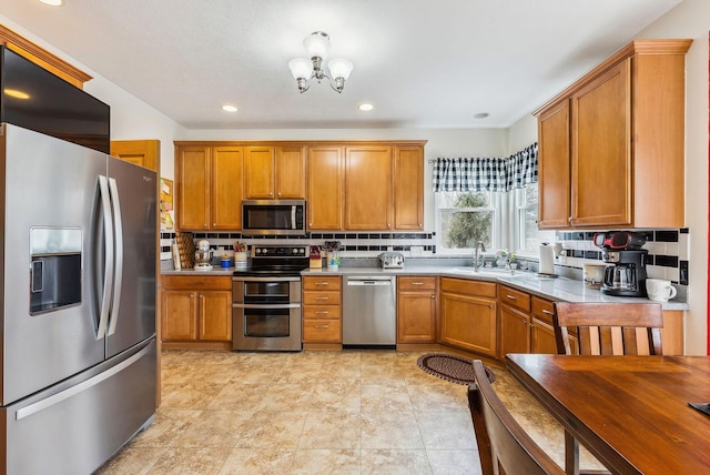 kitchen featuring appliances with stainless steel finishes, brown cabinetry, a sink, and decorative backsplash