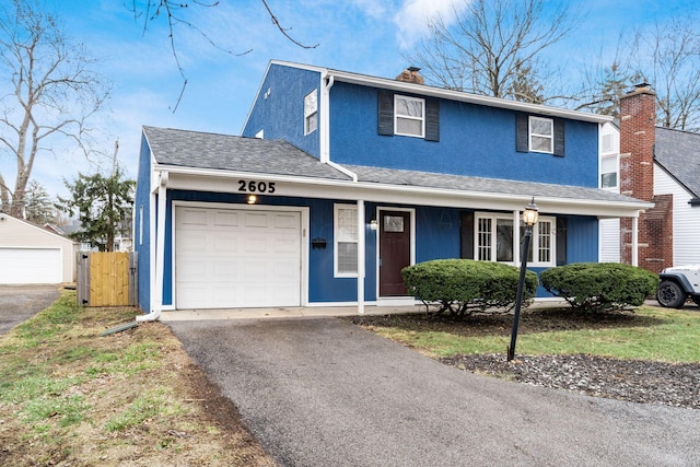 traditional home with a garage, a chimney, aphalt driveway, roof with shingles, and stucco siding