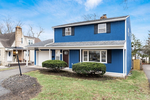 traditional-style house featuring a garage, aphalt driveway, a chimney, and covered porch