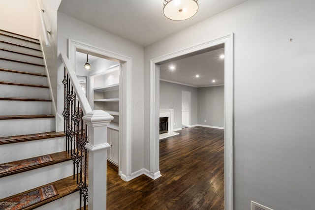 stairs featuring built in features, baseboards, a glass covered fireplace, wood finished floors, and recessed lighting