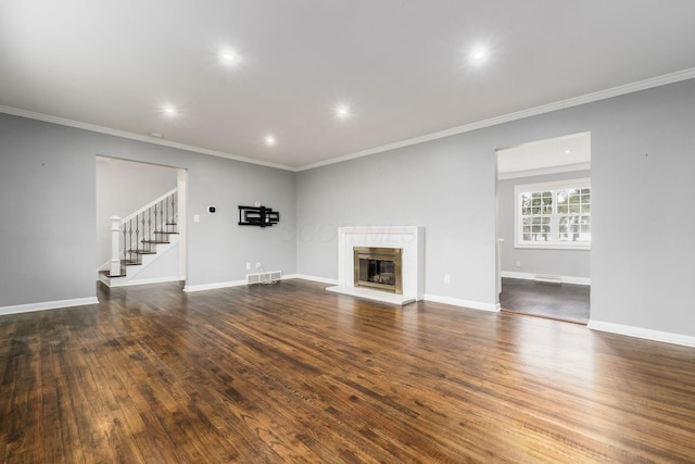 unfurnished living room with a fireplace with raised hearth, wood finished floors, visible vents, baseboards, and stairway