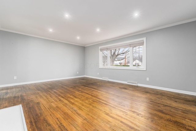 empty room featuring crown molding, wood finished floors, and baseboards