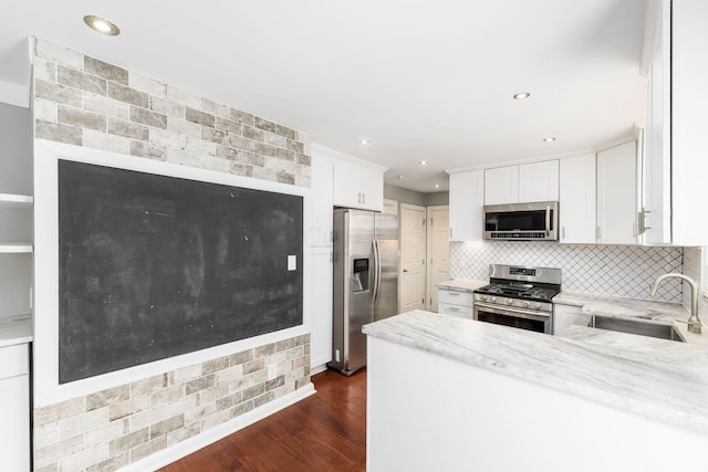 kitchen featuring decorative backsplash, appliances with stainless steel finishes, dark wood-style flooring, white cabinetry, and a sink