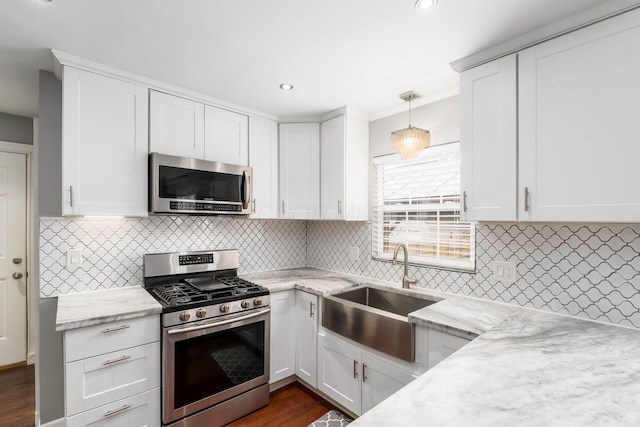 kitchen with appliances with stainless steel finishes, a sink, white cabinetry, and light stone countertops