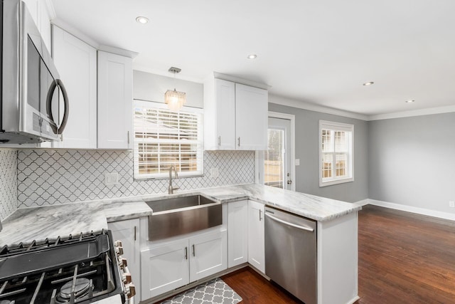 kitchen with a peninsula, white cabinetry, stainless steel appliances, and a sink