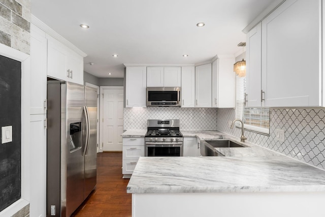 kitchen featuring dark wood-style floors, stainless steel appliances, white cabinets, a sink, and a peninsula