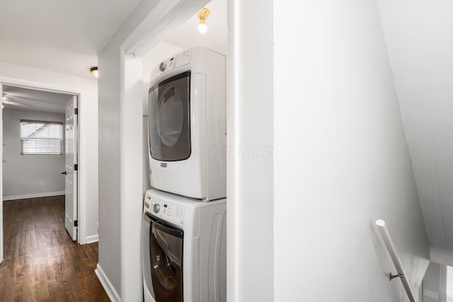 laundry room featuring dark wood-style floors, stacked washer and clothes dryer, baseboards, and laundry area