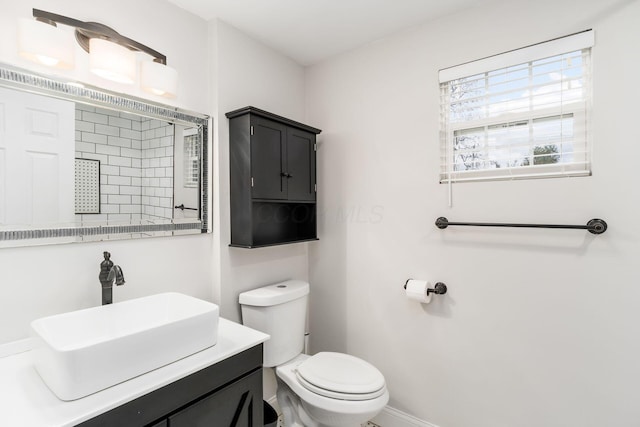 bathroom featuring baseboards, vanity, and toilet