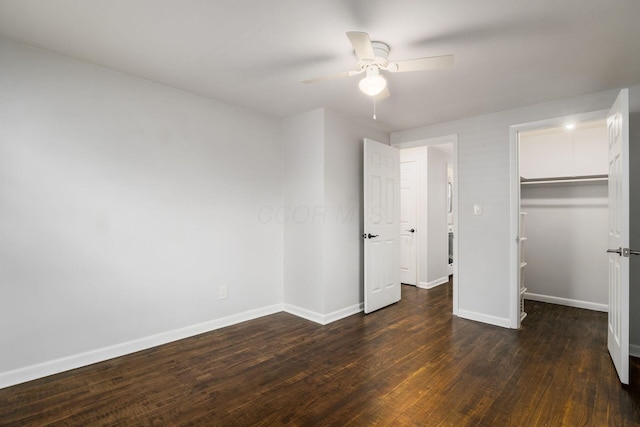 unfurnished bedroom with baseboards, wood-type flooring, ceiling fan, a walk in closet, and a closet