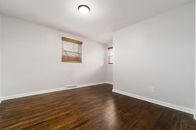 spare room featuring visible vents, dark wood finished floors, and baseboards