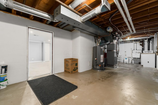 unfinished basement featuring a sink, heating unit, gas water heater, and concrete block wall