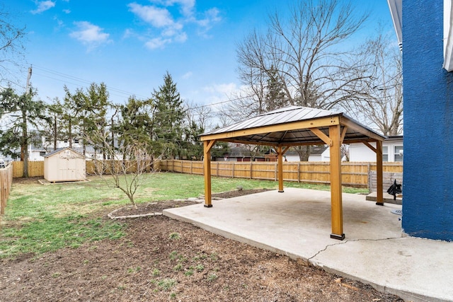 view of yard with an outbuilding, a fenced backyard, a storage shed, a gazebo, and a patio area