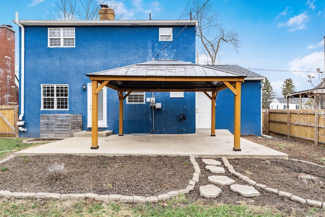 back of property featuring fence, a patio, and a gazebo