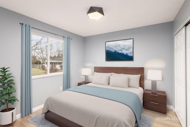 bedroom with light wood-style flooring, baseboards, and a closet