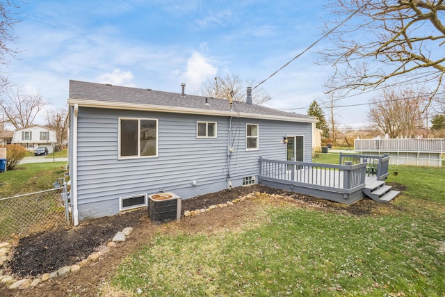 rear view of property with roof with shingles, central air condition unit, a lawn, fence, and a deck