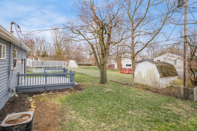 view of yard featuring a shed, a fenced backyard, and an outbuilding