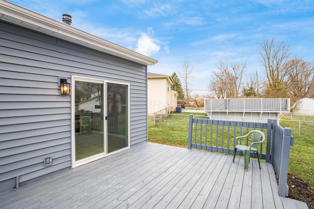 wooden terrace featuring fence and a yard