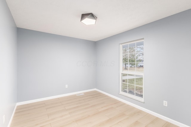 empty room featuring baseboards and light wood finished floors